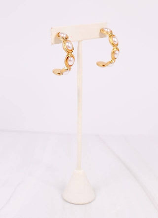 Gold and pearl earring on a white stand with a white background