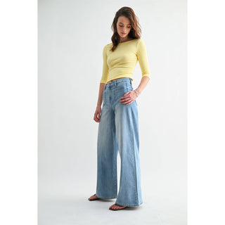 Woman wearing a yellow top and light blue jeans on a white background