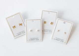 Four pairs of earrings on LINNY CO branded cards against a white background