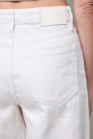 Close-up of white pants with a brand label on a neutral background