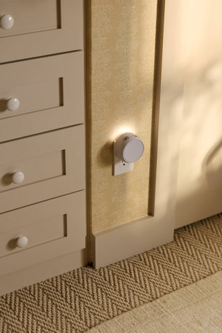 Close-up of a beige cabinet with drawers and a light fixture on a textured wall.