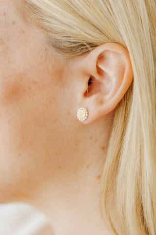 Close-up of a person wearing a gold stud earring with a floral design.