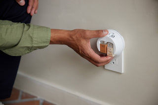 Person inserting a smart plug into a wall socket.