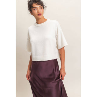 Woman wearing a white top and purple skirt on a plain background