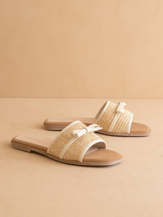 Pair of straw sandals with white straps on a beige background