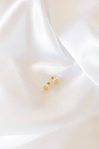 Small gold earring on a white fabric background