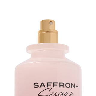 Pink spray bottle with gold nozzle labeled 'SAFFRON+' on a white background