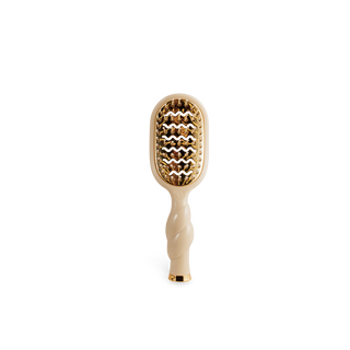 Beige hairbrush with gold bristle head on a white background