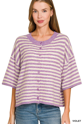 A woman wearing a lavender and cream striped short-sleeve knit top with a button-front closure, paired with blue jeans, against a plain white background.