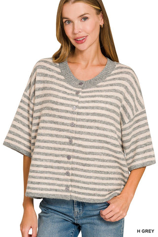 A woman wearing a grey and beige striped short-sleeve button-up cardigan top with blue jeans, shown against a plain white background.