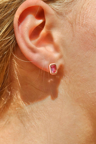 Close-up of an ear wearing a small gemstone earring.