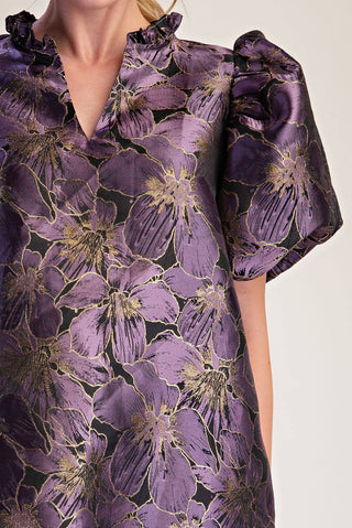Close-up of a purple floral satin dress with gold metallic accents, featuring a ruffled collar and short puff sleeves.