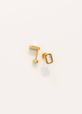 Gold earrings with a small gemstone on a light beige background