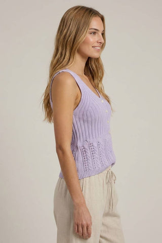 Woman wearing a light purple knitted tank top against a plain background