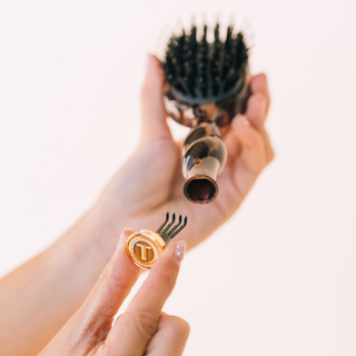 Hand holding a hairbrush with a close-up of bristle tips on a light background