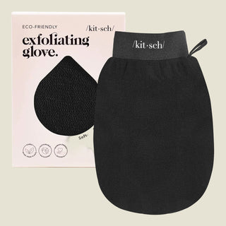 A black exfoliating glove by kit·sch, shown in front of its light pink packaging box. The glove has a dark gray wrist strap with the brand name 'kit·sch' printed in white.