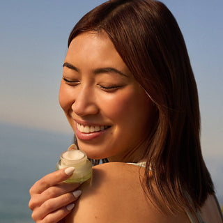 Woman holding a jar of cream with a blurred natural background