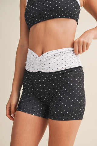 Person wearing a black and white polka dot bikini with a neutral background