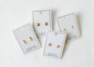 Set of gold earrings on LINNY CO branded cards against a white background