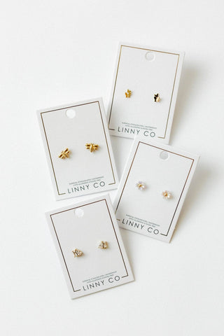 Gold earrings on LINNY CO branded cards against a white background