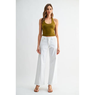 Woman wearing a green tank top and white pants on a white background