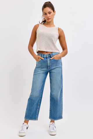 Woman wearing a white tank top and blue jeans on a white background