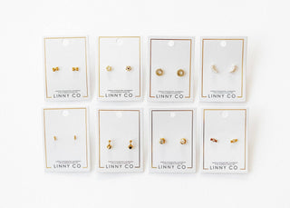 Set of gold earrings on LINNY CO branded cards against a white background