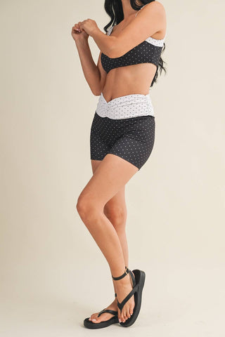 Woman wearing a polka dot top and shorts on a beige background