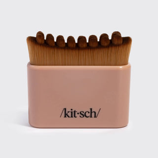 A Kit-Sch makeup brush set in a rectangular blush pink holder, featuring brown bristles and the Kit-Sch logo printed on the front, shot against a light gray background.