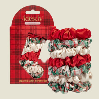 A set of five Kithsch ruched satin scrunchies displayed next to their red plaid retail packaging. The scrunchies feature a mix of solid red satin, cream satin, and green and red plaid ribbons.