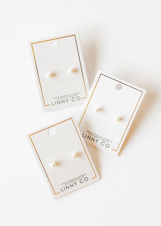 Three pairs of earrings in packaging with 'LINNY CO' branding on a white background