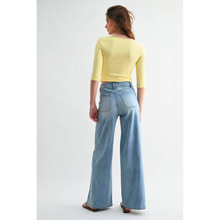 Woman wearing a yellow top and light blue jeans on a white background