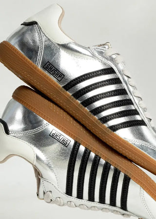 Silver sneakers with black stripes and brown soles on a white background