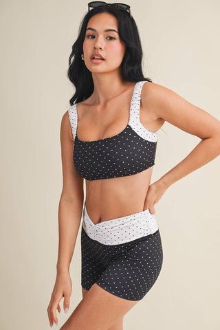 Woman wearing a black and white polka dot bikini set on a beige background