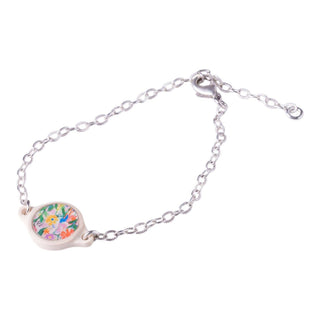 A silver chain bracelet with a small oval charm featuring a colorful floral illustration, set against a plain white background.