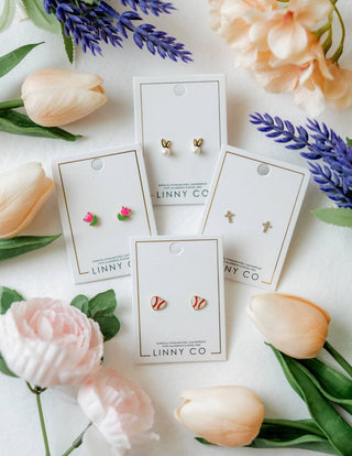 Gold earrings on LINNY CO cards with flowers around