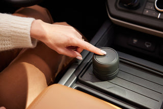 Person using a car cup holder with a black container