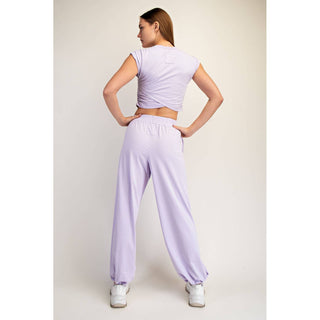Woman wearing a light purple outfit with a matching top and pants on a plain background