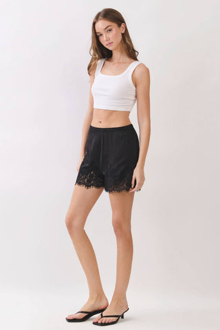 Woman wearing a white crop top and black shorts on a white background