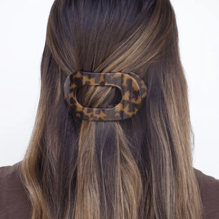 Person with tortoiseshell hair clip in brown hair against a white background