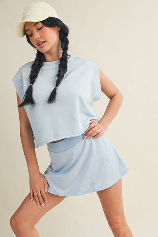 Woman wearing a light blue outfit with a cap on a beige background