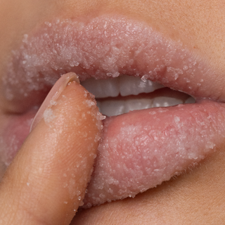 Close-up of lips with a finger on a beige background