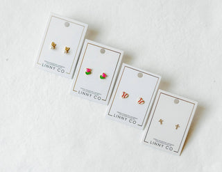 Set of gold earrings on LINNY CO branded cards against a white background