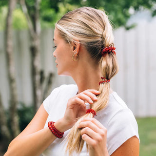 Woman with braided hair wearing red hair ties and bracelets outdoors