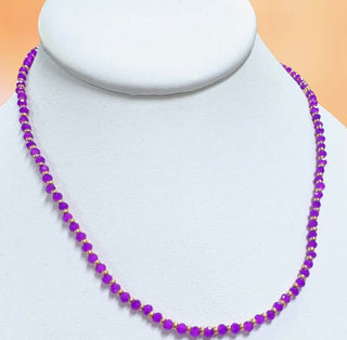 Purple beaded necklace on a mannequin with a beige background
