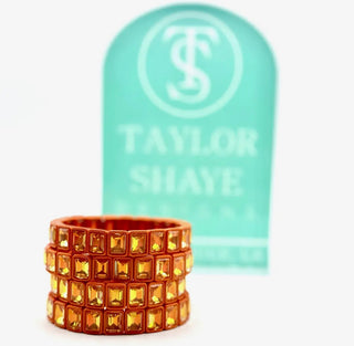 Decorative ring with gold gemstones in front of a Taylor Shave product.