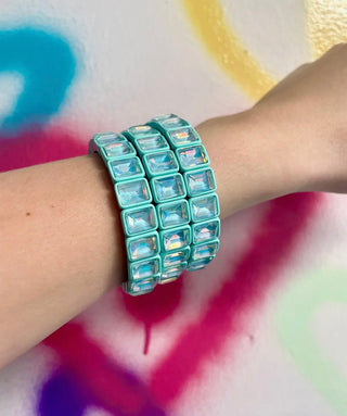 Turquoise beaded bracelet on a wrist with a colorful abstract background