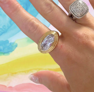Hand wearing two rings with a colorful watercolor background