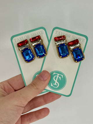 Pair of earrings on a Taylor Shaye card held by a hand