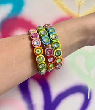 Colorful beaded bracelets on a wrist with a multicolored background